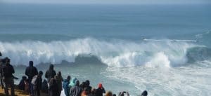 group of people looking at giant waves in Nazare Portugal